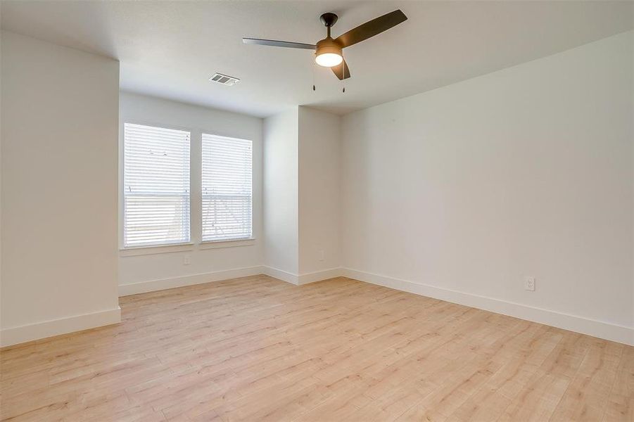 Empty room with ceiling fan and light hardwood / wood-style floors