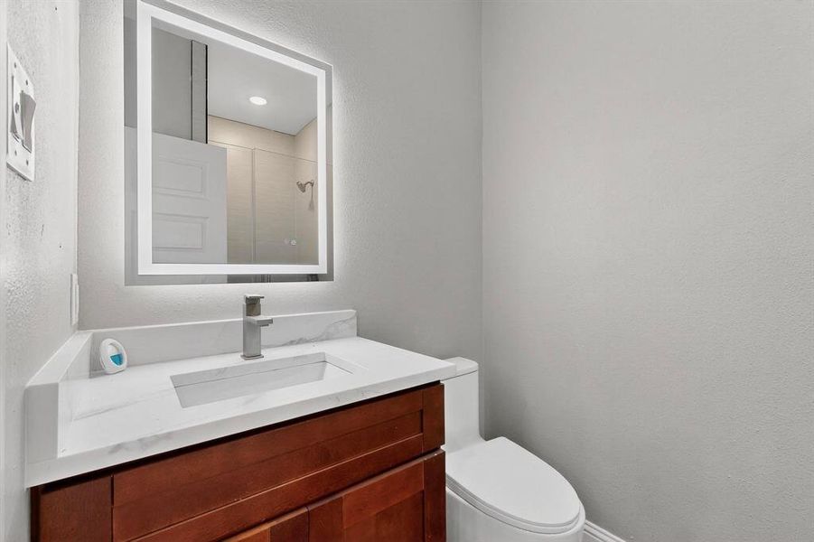 Full bath with a textured wall, vanity, and a shower