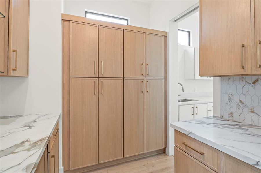Kitchen with light brown cabinetry, plenty of natural light, light stone counters, and tasteful backsplash Kitchen with light brown cabinetry, plenty of natural light, light stone counters, and tasteful backsplash