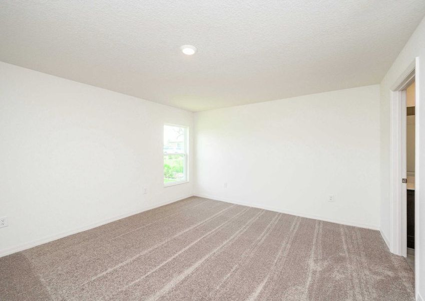 The Caladesi floor plan's spacious master bedroom along with white walls, carpet, a window and an overhead light fixture.