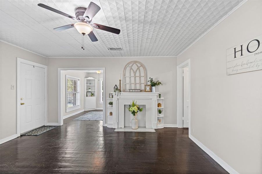 Unfurnished living room with crown molding, dark wood finished floors, and a ceiling fan