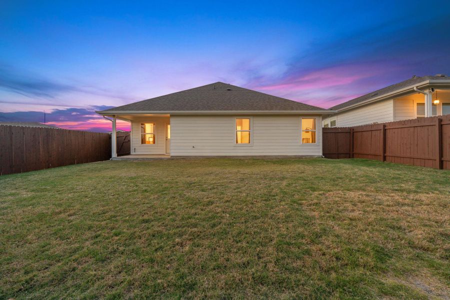 Back of house at dusk with a patio, a fenced backyard, and a shingled roof Back of house at dusk with a patio, a fenced backyard, and a shingled roof