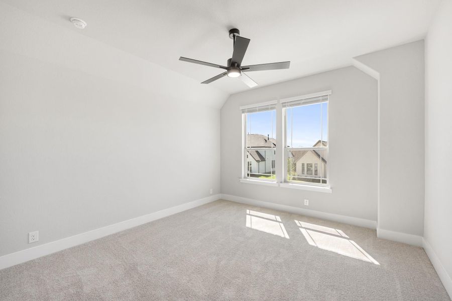 Empty bedroom with vaulted ceiling, ceiling fan, carpet flooring, and double windows Empty bedroom with vaulted ceiling, ceiling fan, carpet flooring, and double windows