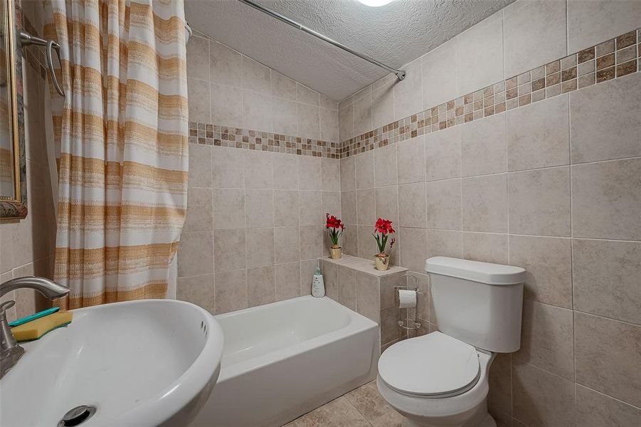 This spacious bathroom features a pedestal sink and tub/shower combo.