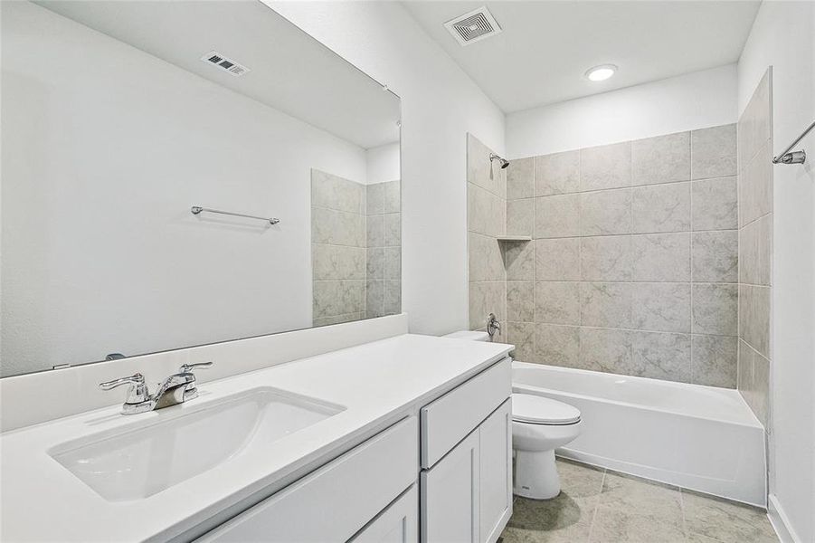 Full bathroom featuring toilet, tiled shower / bath combo, vanity, and tile patterned floors