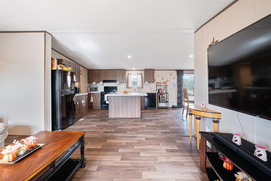 Kitchen featuring light countertops, black appliances, a kitchen island, light wood-style flooring, and recessed lighting