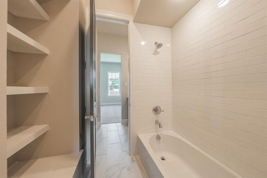 Bathroom featuring a white subway tile shower surround and a built-in bathtub with polished chrome fixtures