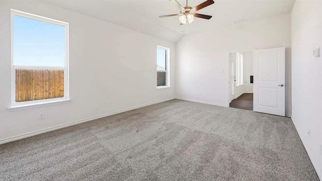 Carpeted empty room with lofted ceiling and a ceiling fan