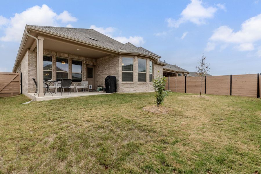 A spacious backyard provides ample room for outdoor activities, complementing a covered patio perfect for relaxation.