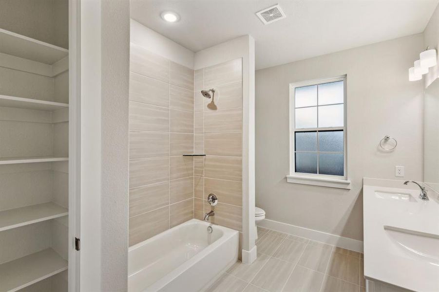 Full bathroom featuring tile patterned flooring, vanity, toilet, and tiled shower / bath