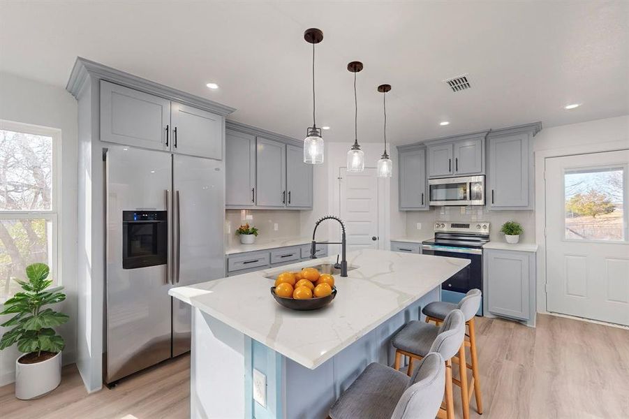 Kitchen with decorative backsplash, sink, stainless steel appliances, and light hardwood / wood-style floors