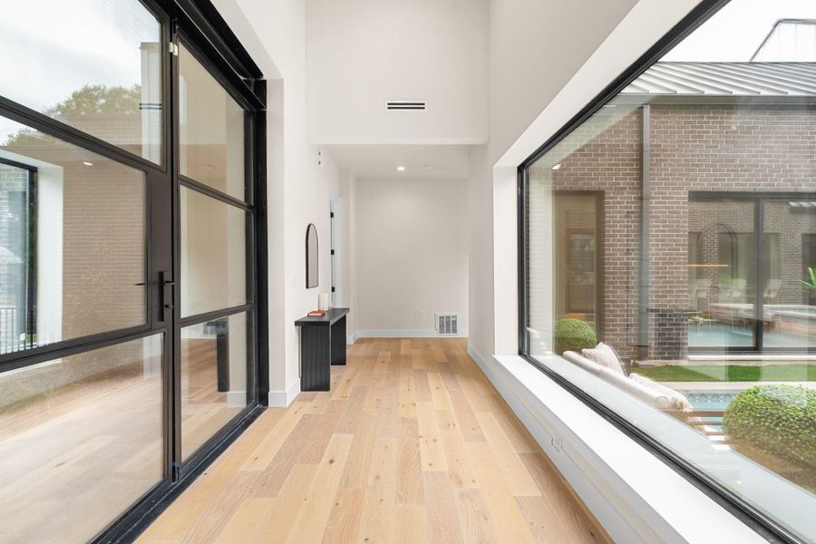 Hallway featuring light wood-finish flooring and high ceilings