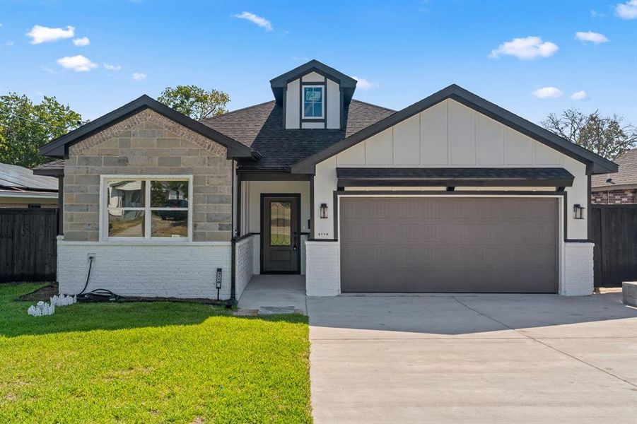 View of front facade featuring a front lawn and a garage