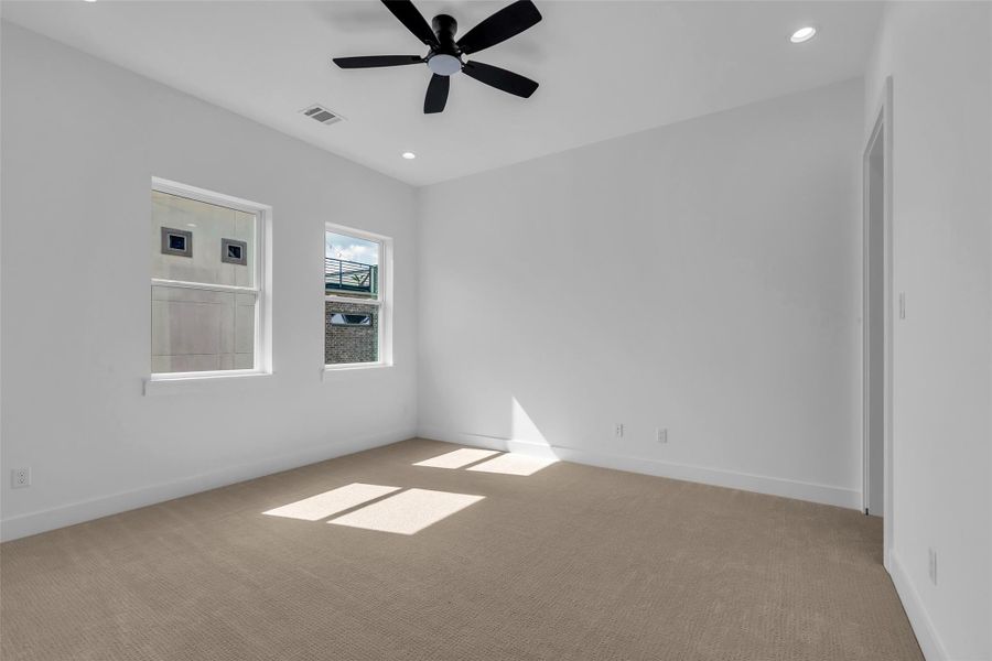 The third-floor primary bedroom features carpeted flooring and several windows that fill the space with natural light. The third-floor primary bedroom features carpeted flooring and several windows that fill the space with natural light.
