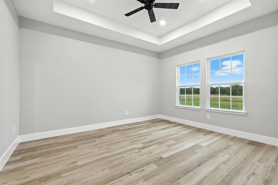 unfurnished bedroom featuring a raised ceiling, light wood-style floors, recessed lighting, and a ceiling fan unfurnished bedroom featuring a raised ceiling, light wood-style floors, recessed lighting, and a ceiling fan