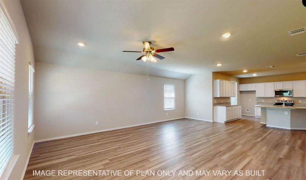 Spacious living area featuring wood-finish flooring, recessed lighting, and a ceiling fan Spacious living area featuring wood-finish flooring, recessed lighting, and a ceiling fan