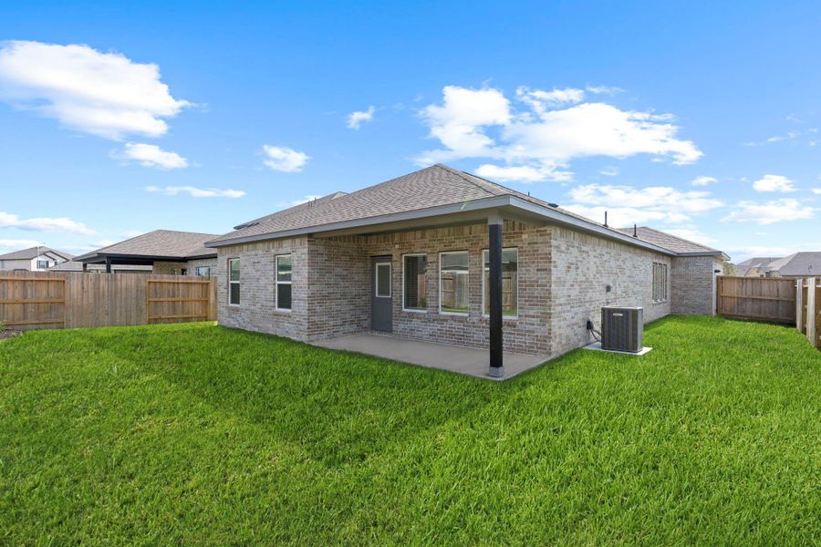 Rear view of this beautiful Sabine home highlights the covered patio, ideal for relaxing or entertaining in comfort. Designed for low maintenance and maximum relaxation, it’s the perfect setting for outdoor gatherings or quiet evenings under the Texas sky.