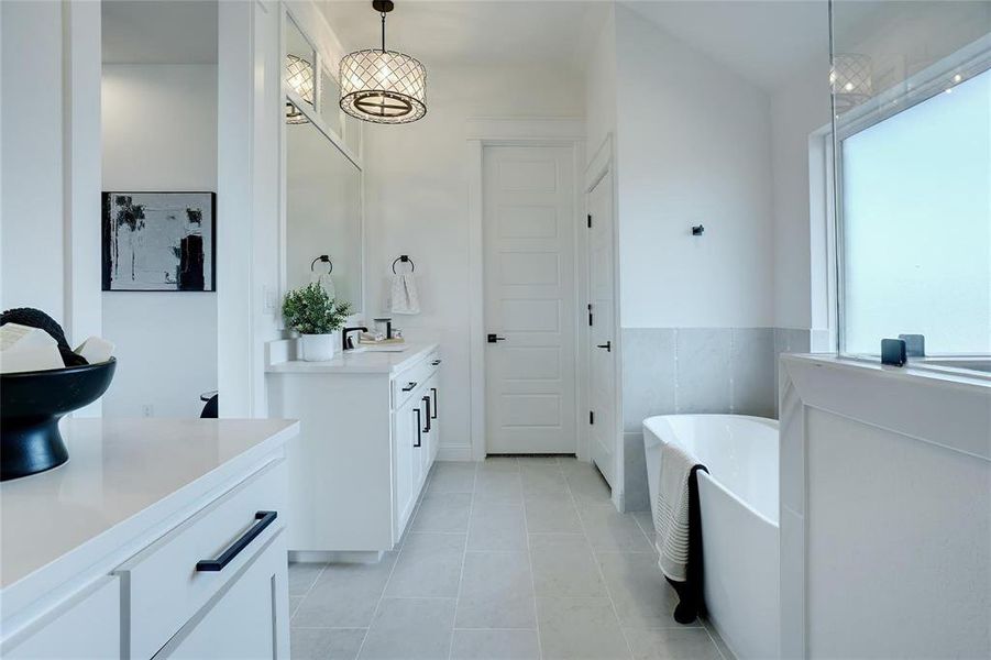 Bathroom with a freestanding bath, vanity, and light tile patterned floors