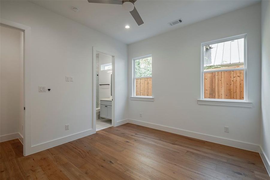 Guest bedroom with wood-type flooring, ensuite bathroom, and ceiling fan