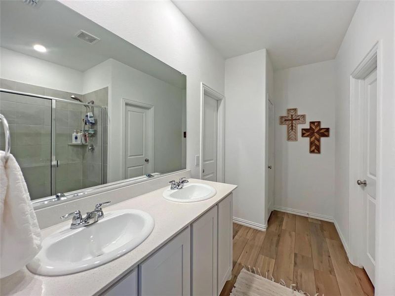 Full bathroom with light wood-type flooring, a stall shower, and double vanity