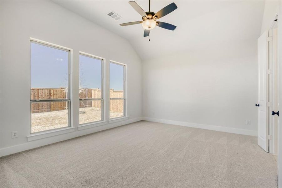 Empty room featuring light colored carpet, a ceiling fan, and lofted ceiling