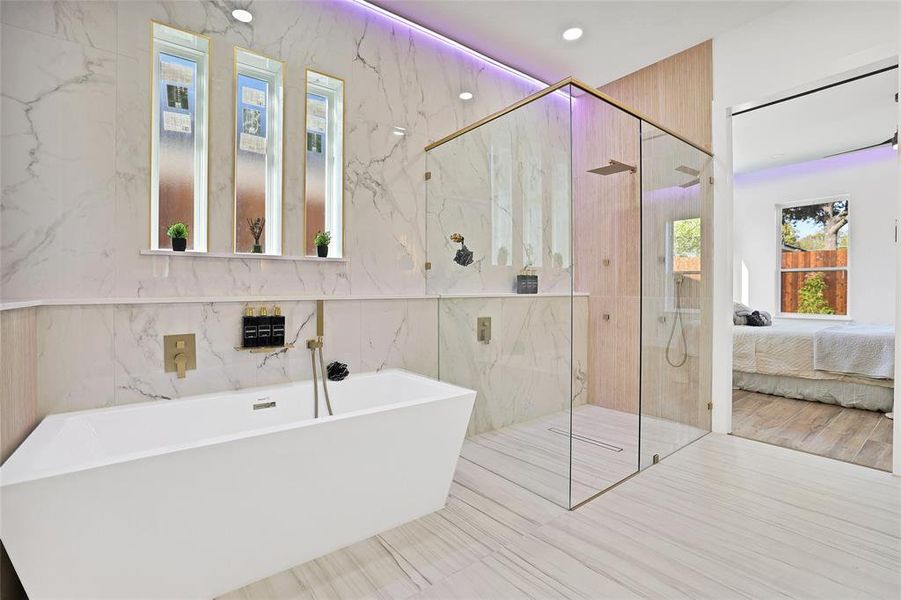 Ensuite bathroom with tile walls, a freestanding bath, a marble finish shower, and recessed lighting