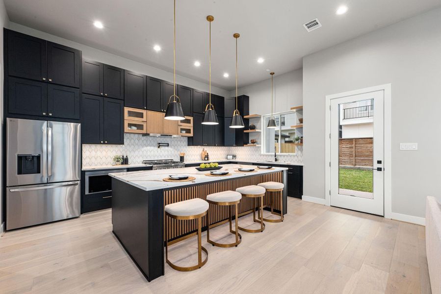 Designer kitchen with quartz waterfall island, stainless appliances, custom cabinetry, and elegant gold accents