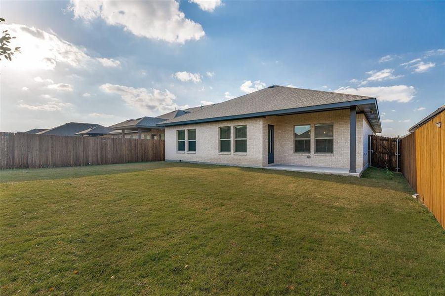 Back of property featuring brick siding, a patio, a fenced backyard, and a shingled roof Back of property featuring brick siding, a patio, a fenced backyard, and a shingled roof