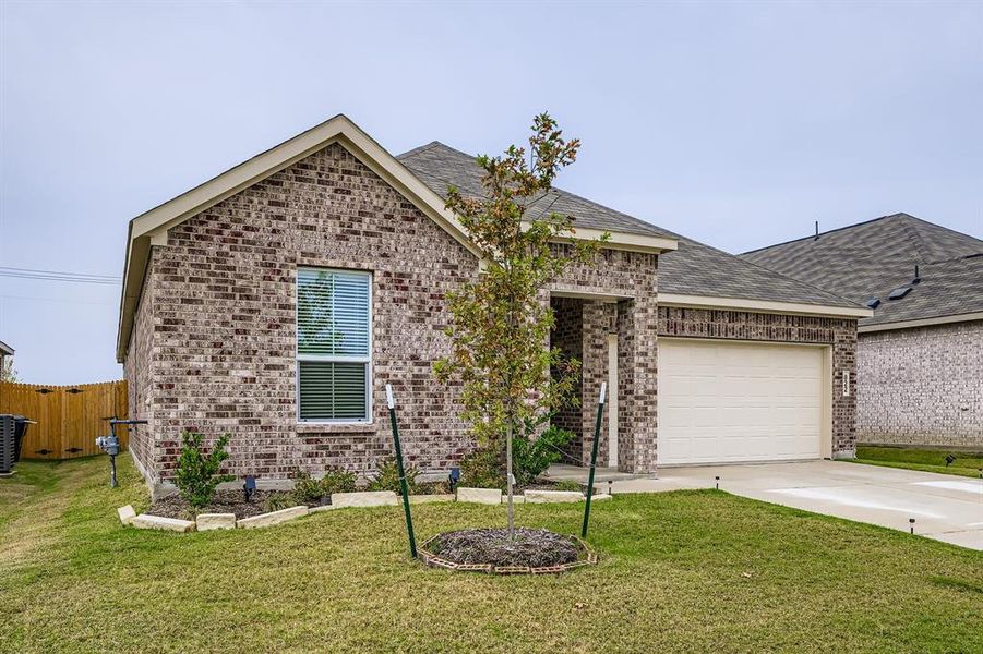 View of front of home featuring brick siding, driveway, and a front yard