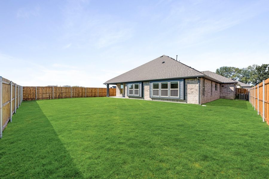 Brick home rear exterior with large fenced backyard and green lawn Brick home rear exterior with large fenced backyard and green lawn