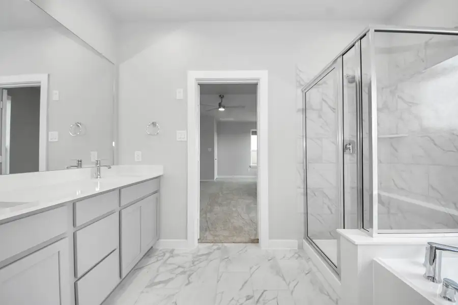 Escape to a spa-like oasis in this primary bathroom. Enjoy a walk-in shower with tile surround, a separate garden tub with custom detailing, and an elegant vanity featuring light countertops, modern hardware, and beautiful recessed lights. Experience luxury and relaxation in every detail! Sample photo of completed home with similar floor plan. Actual colors and selections may vary.