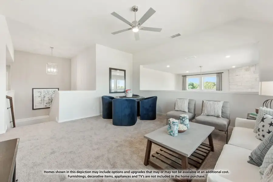 Open upstairs loft with carpet, ceiling fan, seating area, and small dining table with navy chairs
