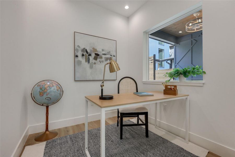 Dedicated office space off the kitchen area, featuring wood flooring and a large window for natural light. Dedicated office space off the kitchen area, featuring wood flooring and a large window for natural light.