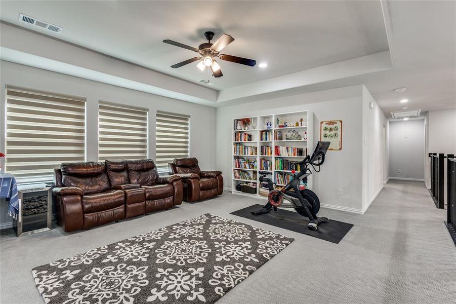 Exercise room with ceiling fan, light colored carpet, a tray ceiling, and recessed lighting