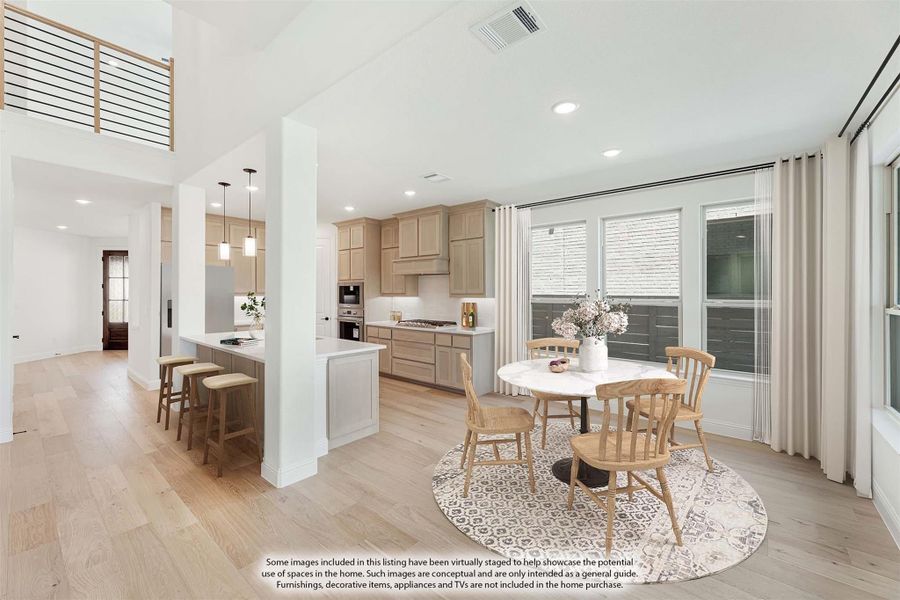 Open dining area with round table and wood chairs next to kitchen with light wood cabinets and hardwood floors