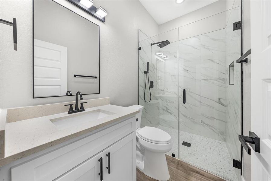 Bathroom featuring a marble finish shower, wood finished floors, vanity, and recessed lighting Bathroom featuring a marble finish shower, wood finished floors, vanity, and recessed lighting