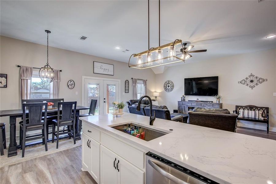 Kitchen featuring french doors, light stone counters, sink, decorative light fixtures, and white cabinetry