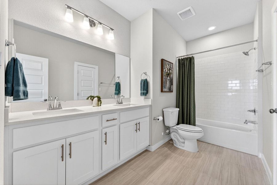 Secondary bathroom featuring double vanity and shower / bath combo