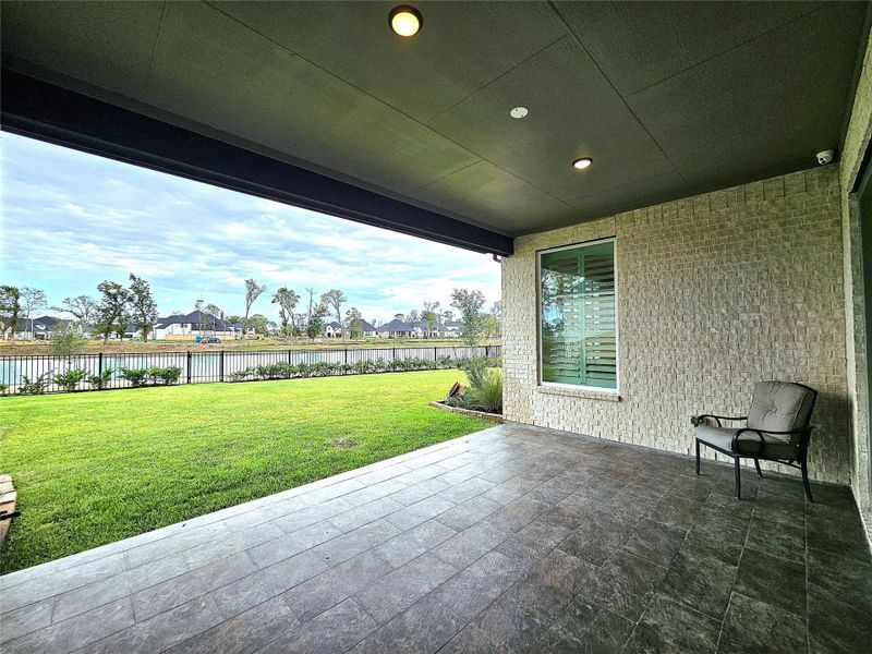 This photo showcases a covered patio with a tiled floor, overlooking a well-maintained lawn and a scenic water view. The space is ideal for relaxing or entertaining, with ample room for outdoor furniture. This photo showcases a covered patio with a tiled floor, overlooking a well-maintained lawn and a scenic water view. The space is ideal for relaxing or entertaining, with ample room for outdoor furniture.