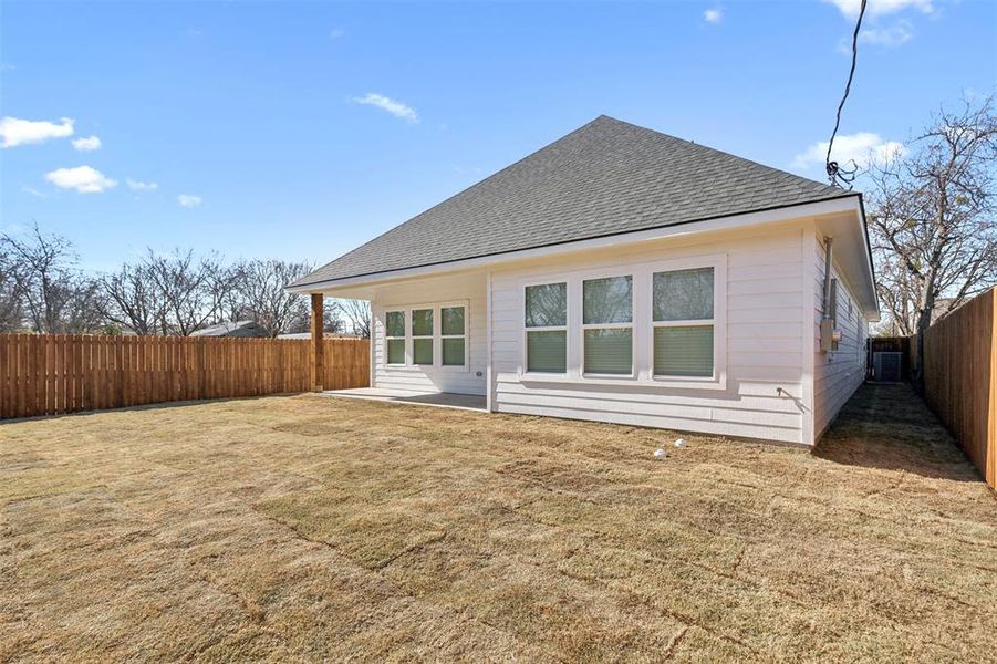 Rear view of property with central AC and a lawn