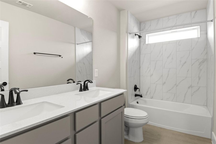 Bathroom with double vanity, toilet, shower combination, and wood finished floors Bathroom with double vanity, toilet, shower combination, and wood finished floors
