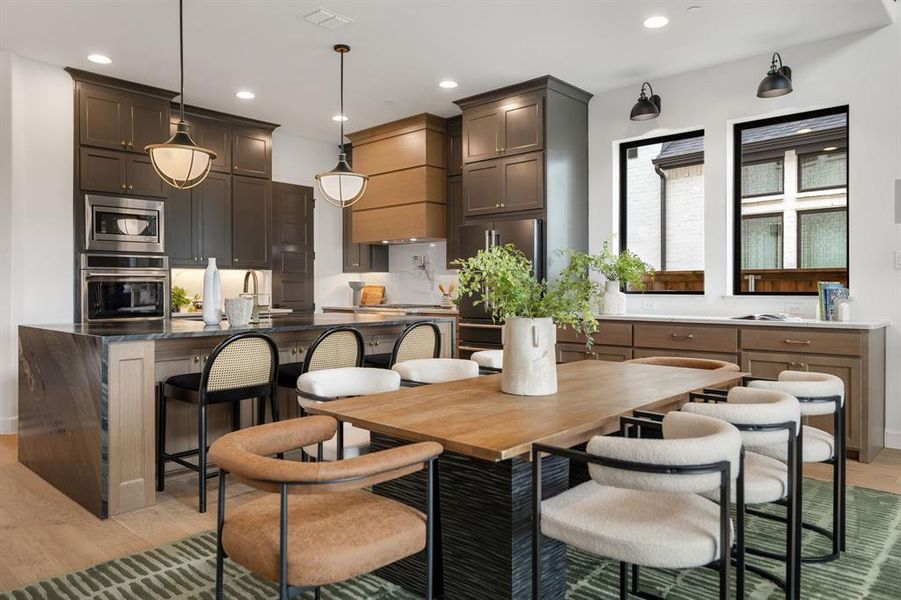 Kitchen with light wood-style floors, recessed lighting, stainless steel appliances, an island with sink, and dark countertops Kitchen with light wood-style floors, recessed lighting, stainless steel appliances, an island with sink, and dark countertops