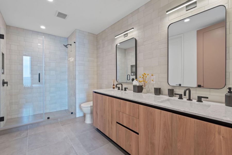Representative Photo. Primary Bath with spacious double vanity, floor to ceiling tile, and a walk in shower
