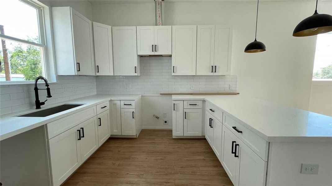 kitchen featuring white shaker cabinets, sleek black hardware, subway tile backsplash, and quartz countertops. It's equipped with a deep sink and has ample storage space.