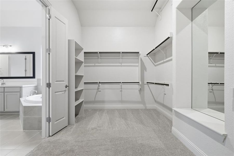 Walk in closet with light carpet and light tile patterned floors