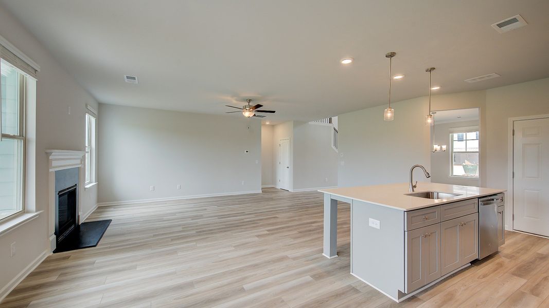 Meridian II open-concept living space connecting kitchen and family room with LVP flooring at Brighton in Locust Grove, GA.