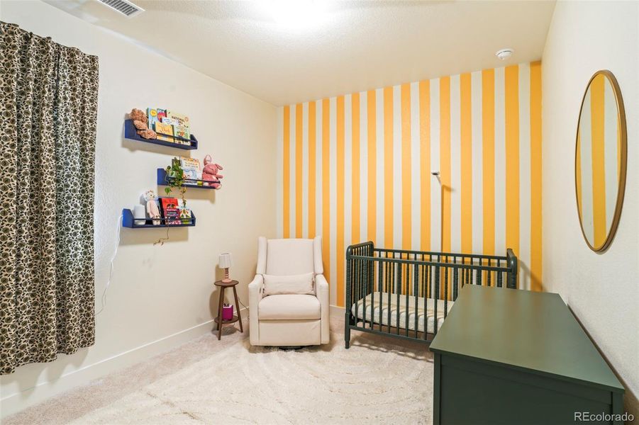 Charming secondary bedroom with playful design and soft finishes, ideal as a nursery or guest space in this Three Hills home