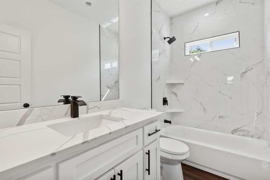 Full bathroom with hardwood / wood-style floors, vanity, toilet, and tiled shower / bath combo