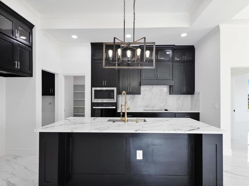 Kitchen featuring stainless steel oven, built in microwave, a chandelier, light marble finish flooring, and backsplash