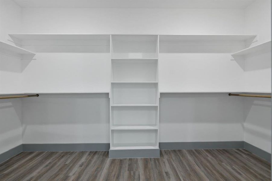 Walk-in closet featuring built-in shelving, hanging rods, wood-finish flooring, and a neutral color palette